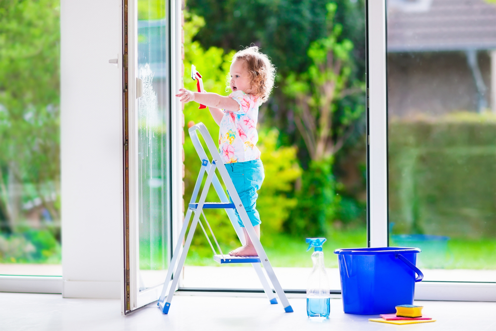 Ein kleines Kind putzt ein französisches Fenster